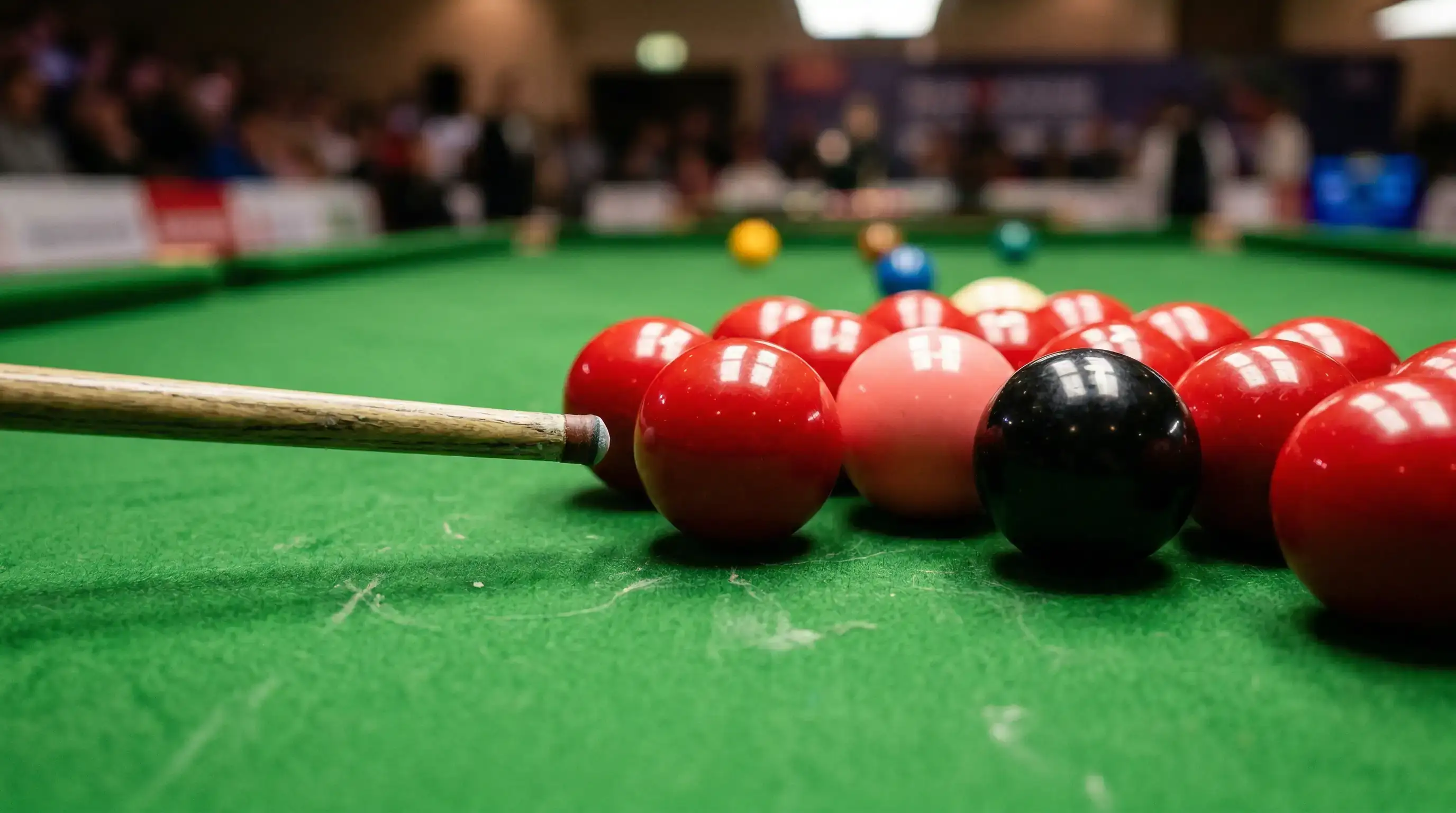 Kolorowe bile snookerowe ułożone na zielonym suknie stołu z widocznym kijem